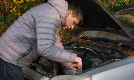 Man repairing his old car and demounting the empty battery to prepare the vehicle for the cold seasonの写真素材