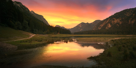 Sunset and orange glow at a Lake surrounded with scenic mountains in Bavaria, Germany. Panoramic...