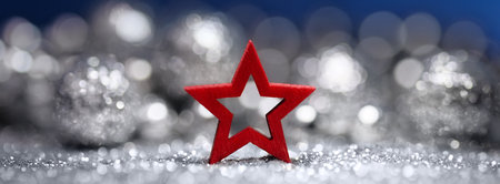 Red Christmas star on glittering silver surface, with shimmering ornaments  as a white and blue backgroundの写真素材
