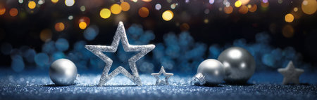 Silver Christmas ornaments on glittering blue surface, with festive lights on dark background