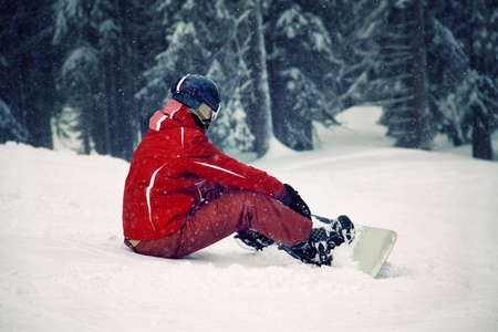 Snowboarder sitting on the snow and watching beautiful natureの写真素材