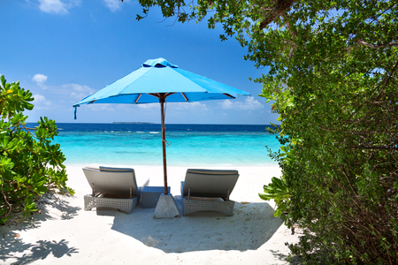 Two lounge chairs with sun umbrella on a beach. Maldives resortの写真素材