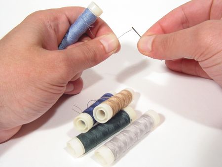 Hands putting the thread through the needle