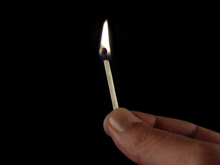 Fingers holding a match infront of black background