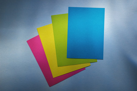 Stack of Small Blue, Green, Pink, Yellow Paper Sheets on Shaded Backdrop. Bright Summer Background...