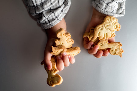 Childrens hands hold dinosaur shaped cookiesの写真素材