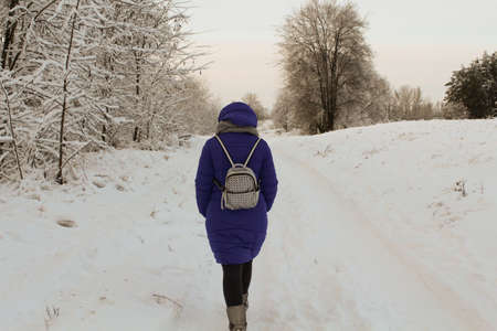 Beautiful girl is walking in the winter forestの写真素材