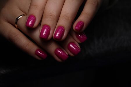 Closeup of hands of a young woman manicure on nails against white background