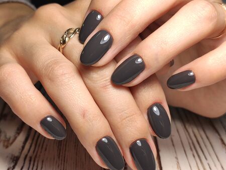 Closeup of hands of a young woman with dark red manicure on nails against white backgroundの写真素材