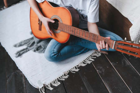 A girl plays a wooden guitar, close-up. Playing the guitar. Guitar in handの写真素材
