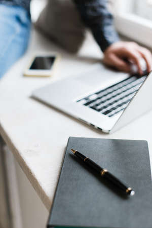 Daily planner close-up. A man is working on a laptop. Work at home on the Internet.