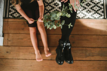 Feet of adults and children on a wooden background. Beautiful female legs. Mother and daughter sitting on the floorの写真素材