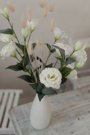 White flowers in a vase upright. A beautiful vase of flowers stands on the table. Interior details.の写真素材