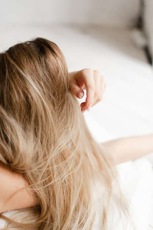 young woman sleeping on white lingerie in bed at home, top view. strong blond hair outline.の写真素材