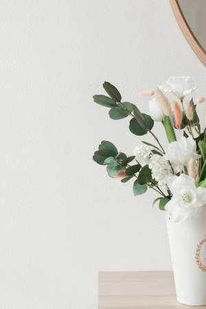 decorative flowers in a vase on a white wall background. interior