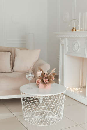 artificial decorative flowers in a pink box and a glass of wine on a white table. interiorの写真素材