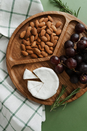 Camembert mold cheese, nuts and grapes on a wooden round plate. A healthy and wholesome meal....