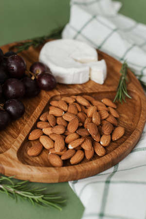 Mildewed cheese, nuts and grapes. A tasty and healthy dish on a green background. Useful and healthy food in wooden dishes.の写真素材