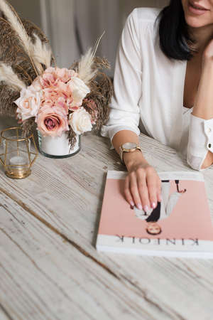 girl sitting at a table with artificial flowers. Wooden table. Wood textureの写真素材