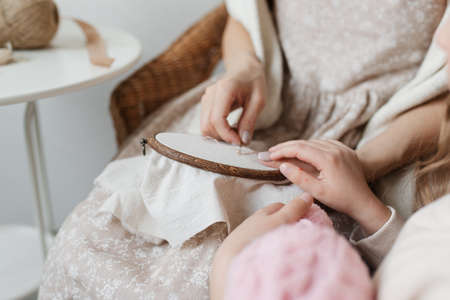 Parent and child hands to embroider. Mother and daughter embroidery. Hands with embroidery close-up on light background.の写真素材