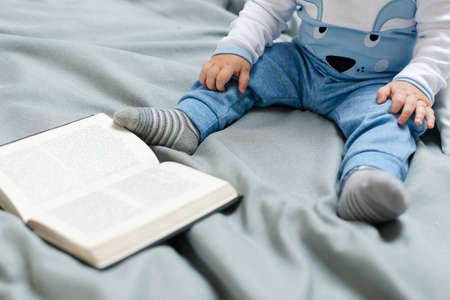 small child with a book sits on the bed. Small childrenの写真素材