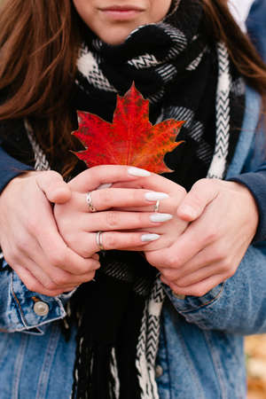 girl holding a red autumn leaf in her hands. Jean jacket. Autumnの写真素材