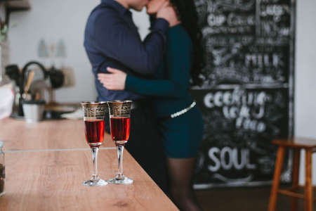 a man and a woman are kissing against the background of glasses of wineの写真素材