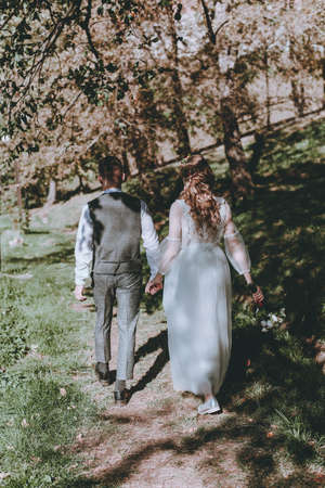 stylish bride and groom are walking along the road among the trees. Wedding styleの写真素材