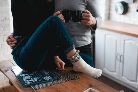 man and woman drink tea on a wooden table. Stylish apartment interiorの写真素材