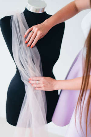 The tailor works with manikin and light fabric. Tailor work process.の写真素材