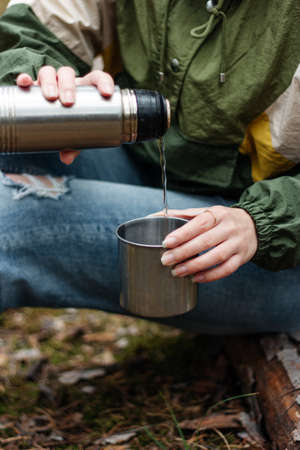 girl pours aromatic tea from a  in  forest. Picnic in  pine forestの写真素材