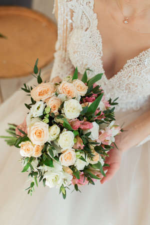 the bride in a white dress is holding a bridal bouquet. Close-up bouquet. Morning of the brideの写真素材