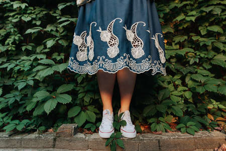 female legs in sneakers in a blue dress on a background of grass. Lifestyleの写真素材