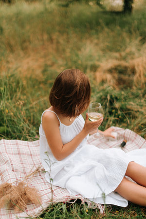 picnic on the grass, a girl in a white dress drinks champagne, summerの写真素材