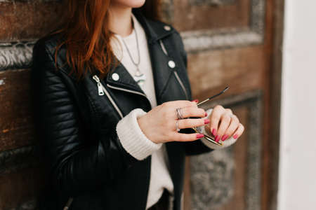 girl in a black leather jacket posing against a wall backgroundの写真素材