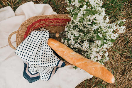 picnic on the grass, a baguette and a bouquet of flowers in a basket. Summer