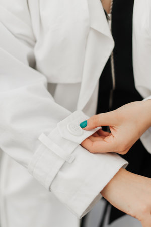 the girl straightens the sleeve of her white coat. Clothes close-up