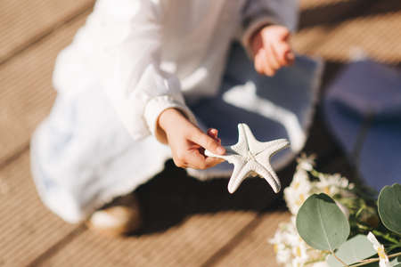 little girl sitting and holding a starfish summer and childrenの写真素材