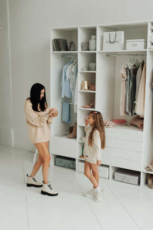 beautiful mom and daughter with bare legs in beige sweaters in the studioの写真素材