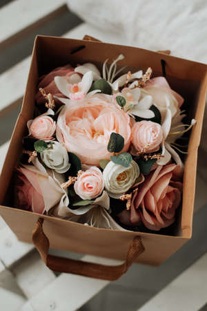 artificial decorative flowers in a paper box on a table close-upの写真素材