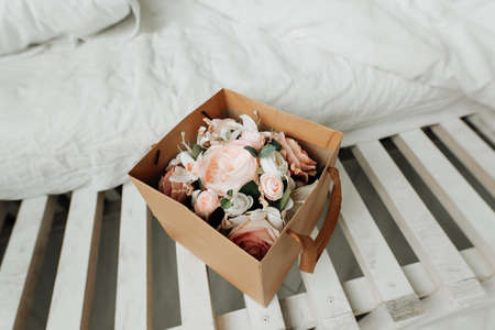 artificial decorative flowers in a paper box on a table close-up