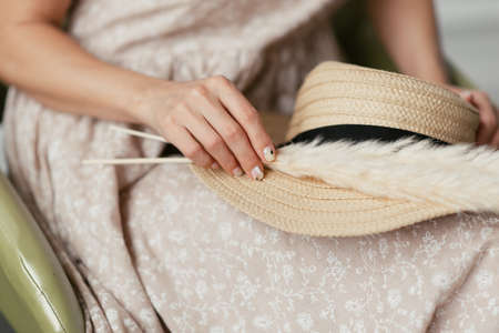 Dried flowers in the hands of the girl against the background of a dress and a straw hatの写真素材