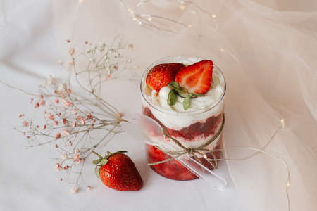 sweet dessert in a glass and strawberries close-up on a white tableの写真素材