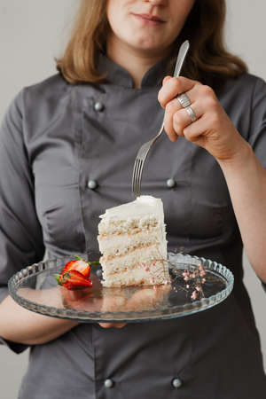 a girl with a fork holds a piece of cake on a transparent tray in her handsの写真素材