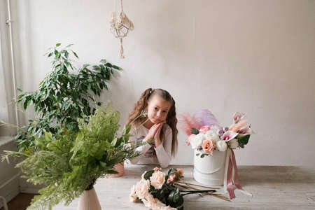 cute little girl stands next to the table with bouquets of flowersの写真素材