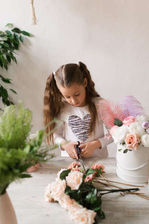 cute little girl florist collects a bouquet of flowers at the tableの写真素材
