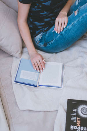 beautiful female hands and an open book lie on the bedの写真素材