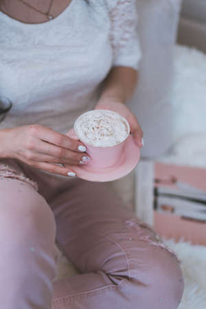 beautiful female hands with manicure hold a pink mug with coffeeの写真素材