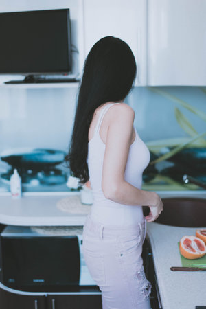 young brunette girl in purple top is cooking in the kitchenの写真素材