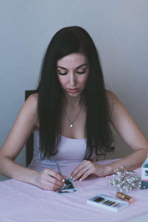 cute brunette girl in purple top sits at the table and does somethingの写真素材